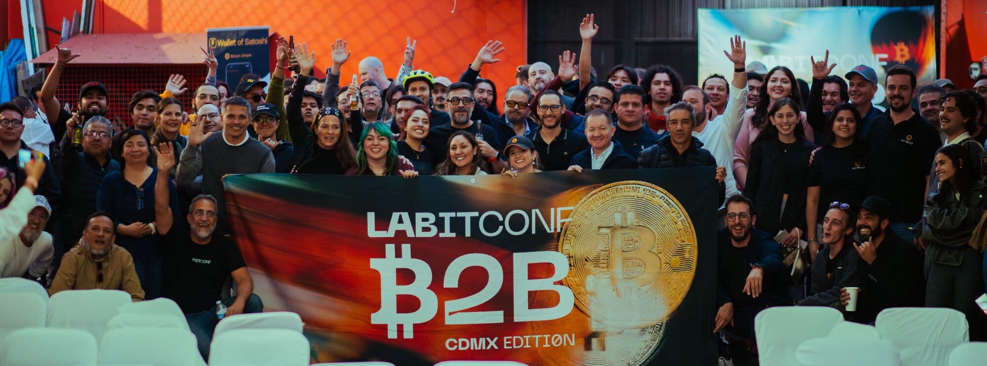 El público de LABITCONF B2B CDMX, manos arriba, detrás del banner